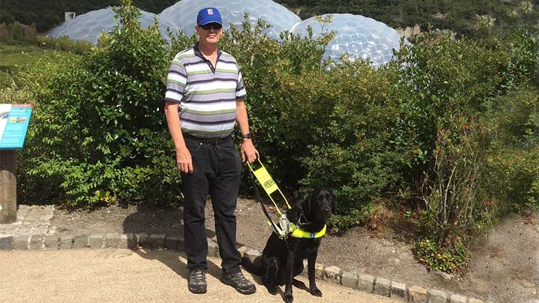 Guide-dog-owner-and-guide-dog-standing-in-front-of-the-Eden-project-biomes