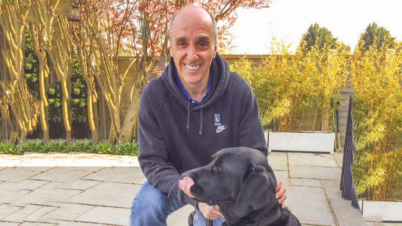 Guide dog owner and guide dog sitting together in a garden