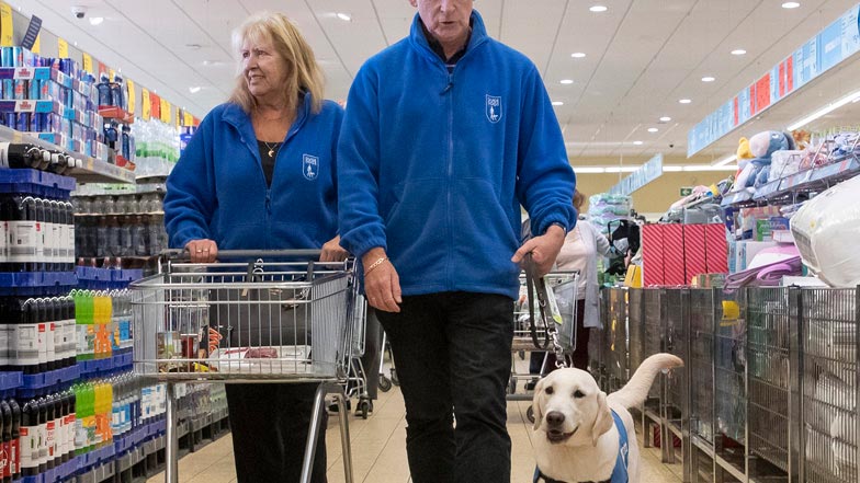 Eve walking next to her Guide Dogs trainers in a supermarket Eve walking next to her Guide Dogs trainers in a supermarket