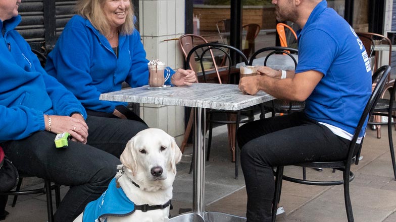 Eve sitting outside a cafe with Guide Dogs trainers Eve sitting outside a cafe with Guide Dogs trainers
