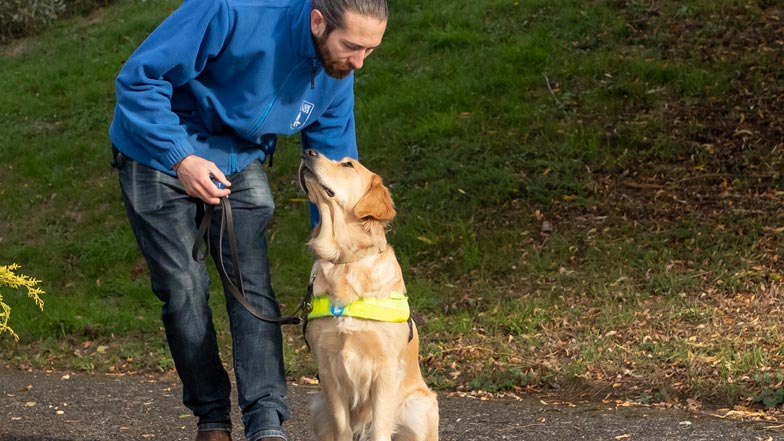 Joy sitting on the kerb next to Che, a Guide Dogs trainer Joy sitting on the kerb next to Che, a Guide Dogs trainer