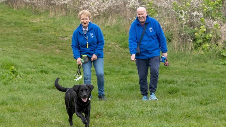 Milo excitedly running towards the camera with his two trainers in the background Milo excitedly running towards the camera with his two trainers in the background
