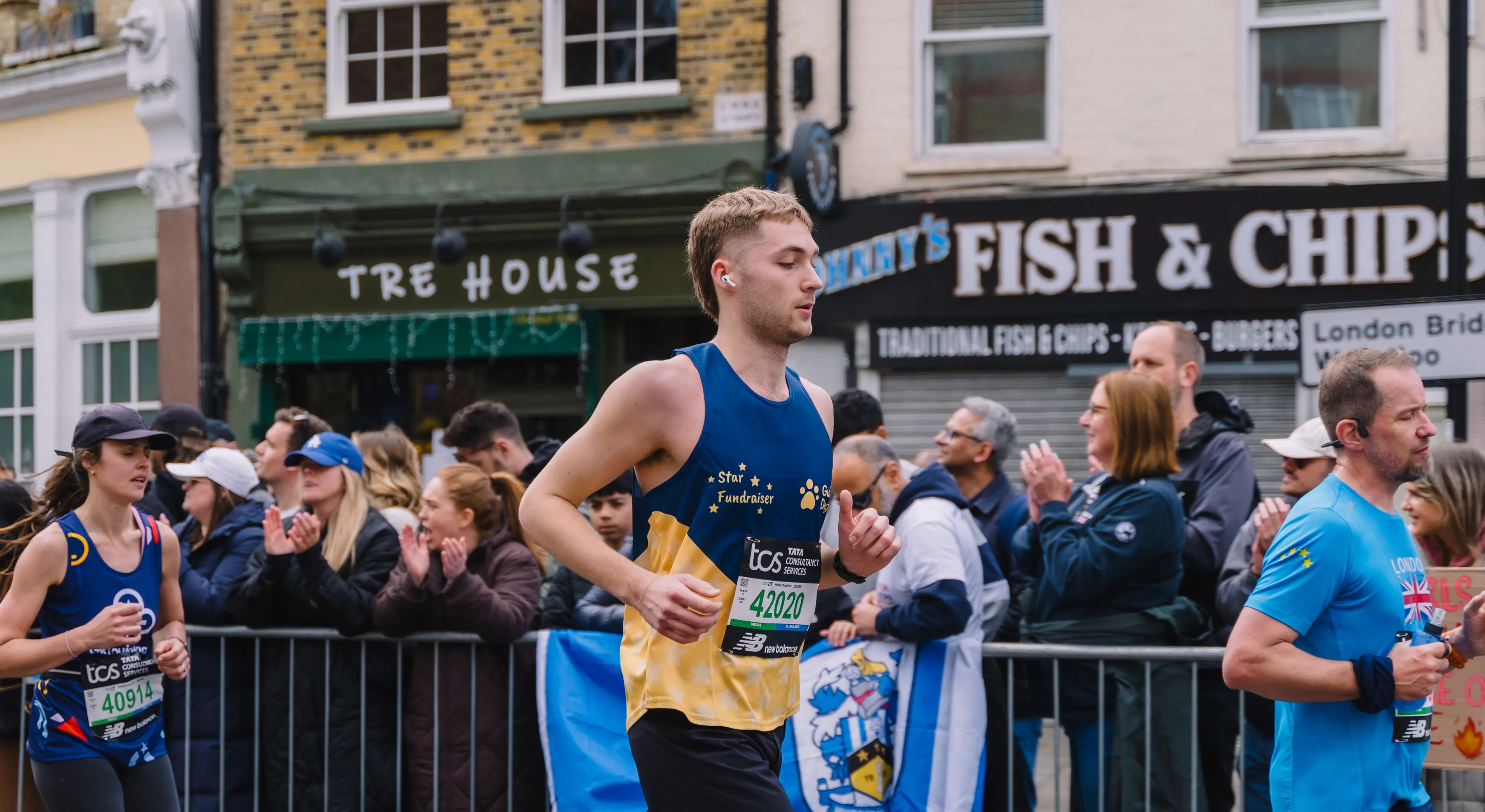 A Guide Dogs London Marathon runner runs past a crowd.