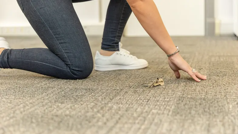 A person bending down to locate their dropped keys.
