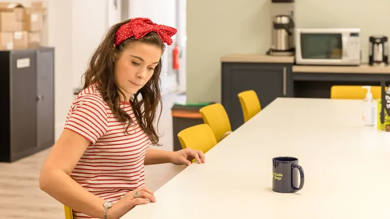 A woman using the grid technique to locate a mug of tea on a table.