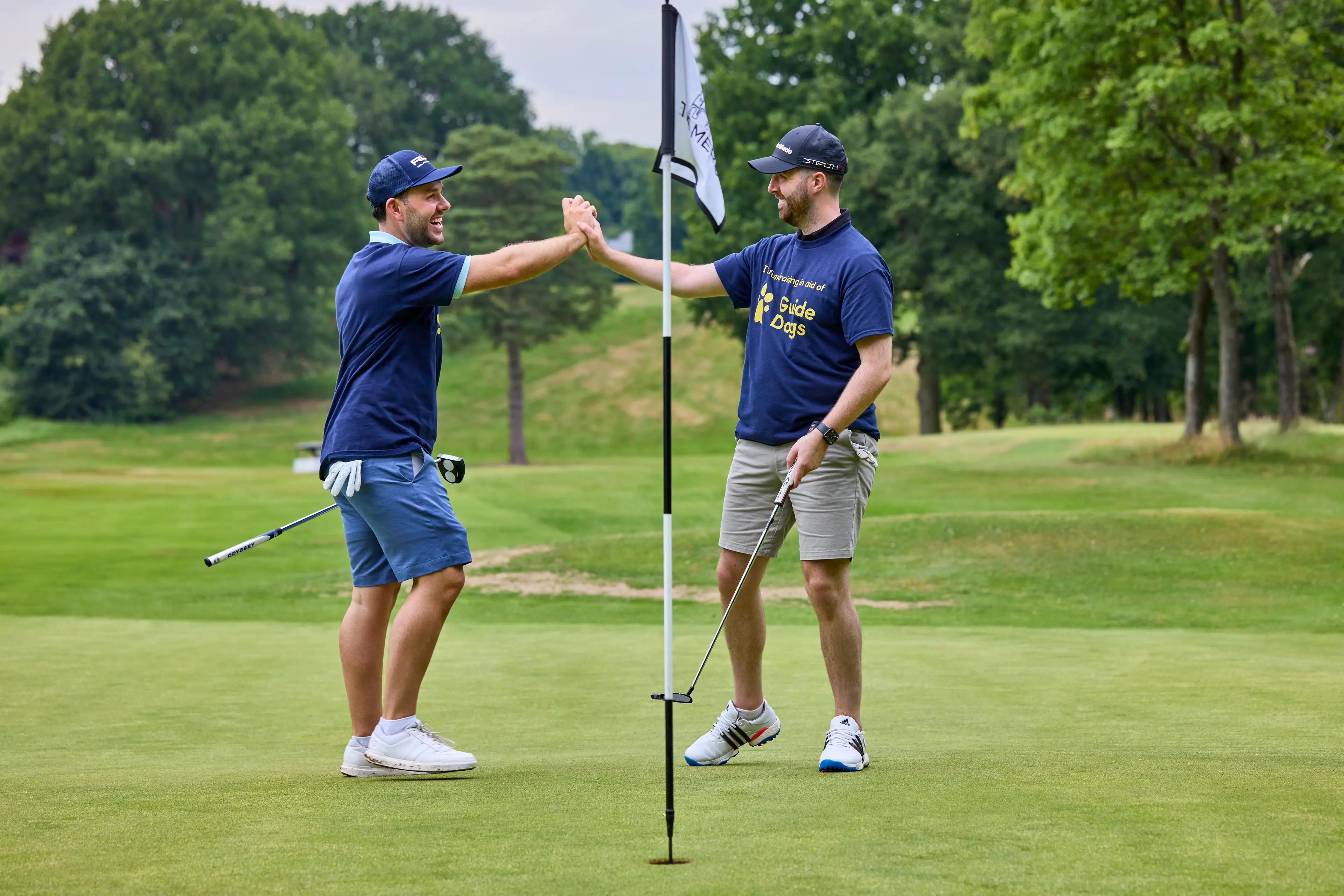 Two men high-five on a golf course.