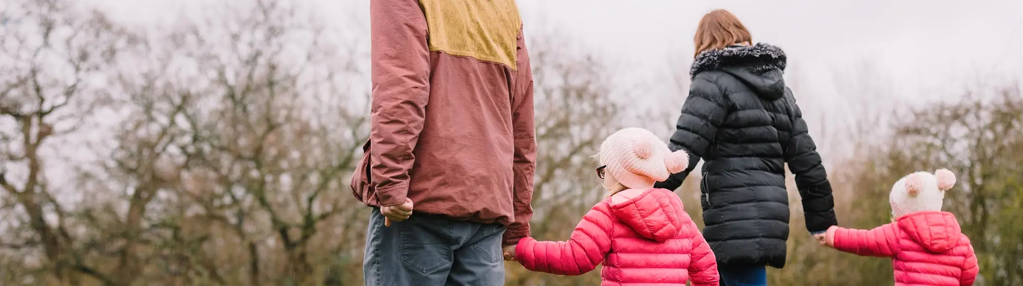 A mother and father walk with their two children outside