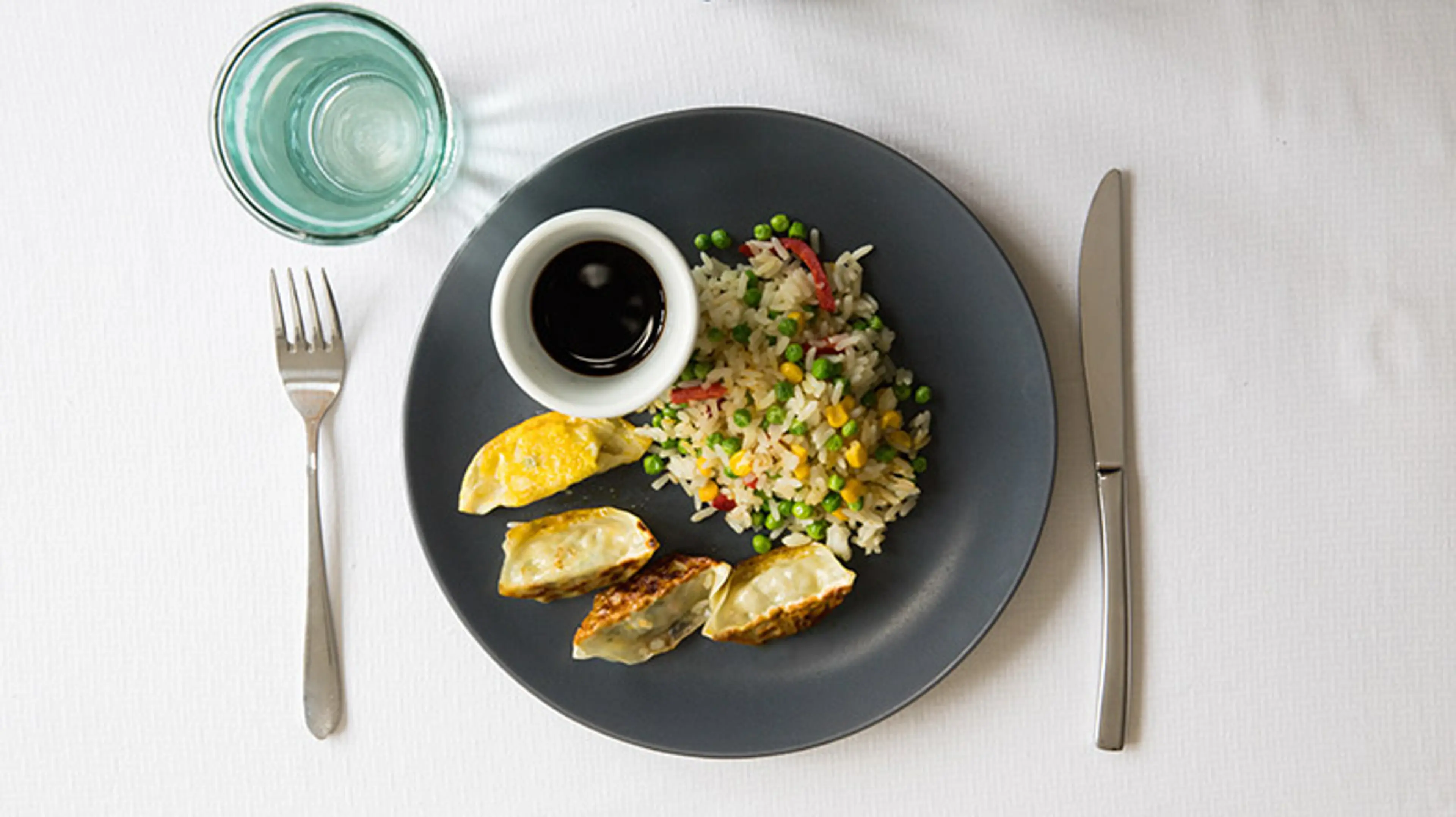 An image of a meal on a dark plate on a table with a white table cloth.