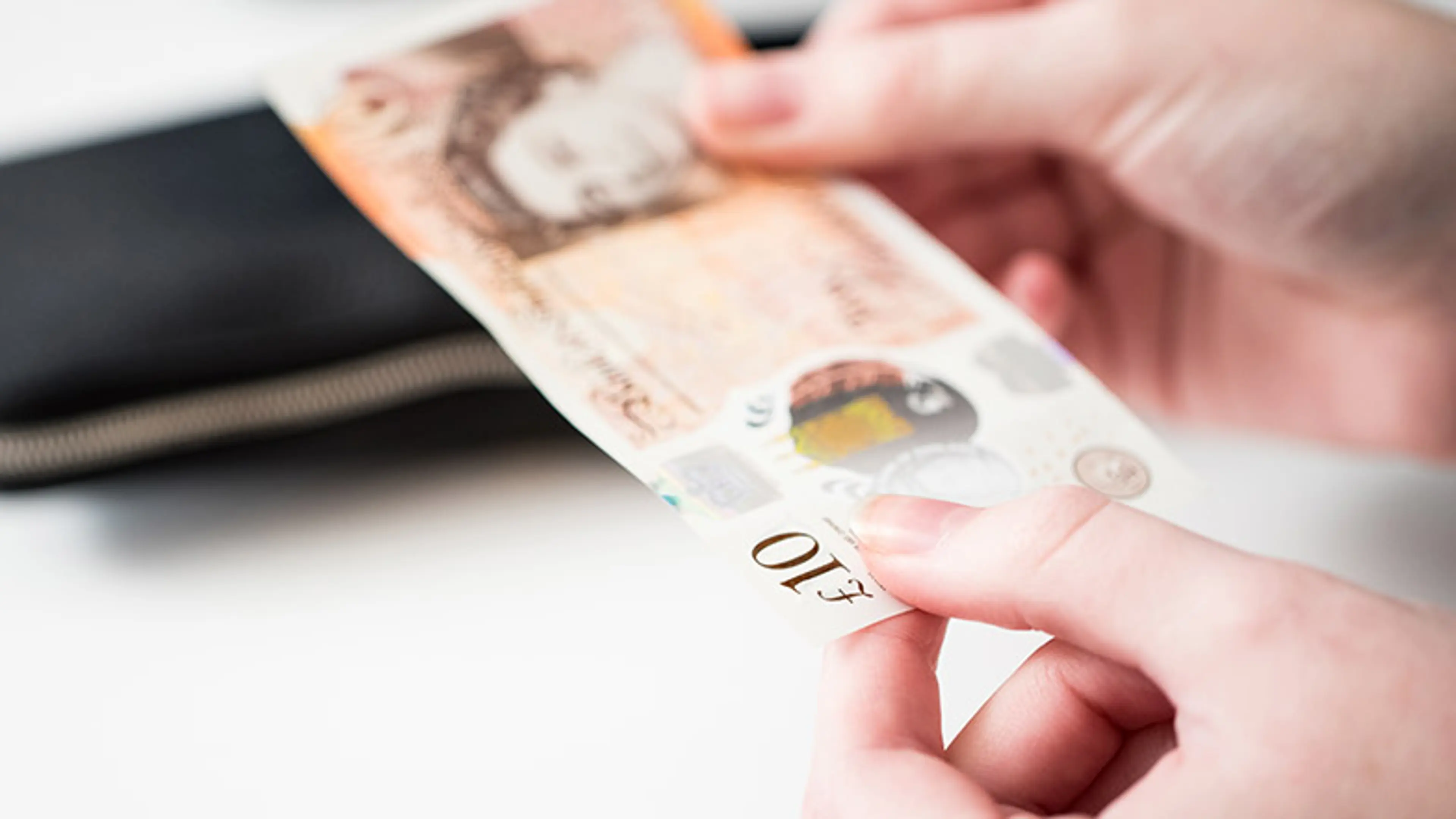 An image of a person holding a 10 pound banknote