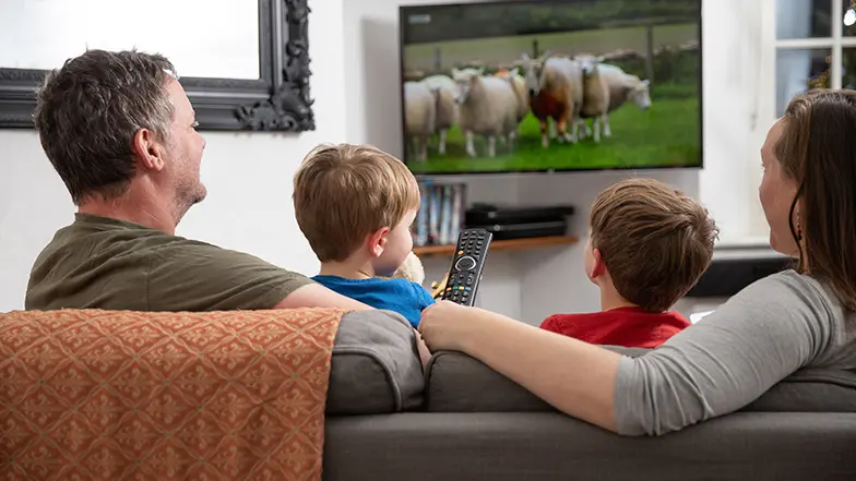 A family sitting on the sofa together watching television