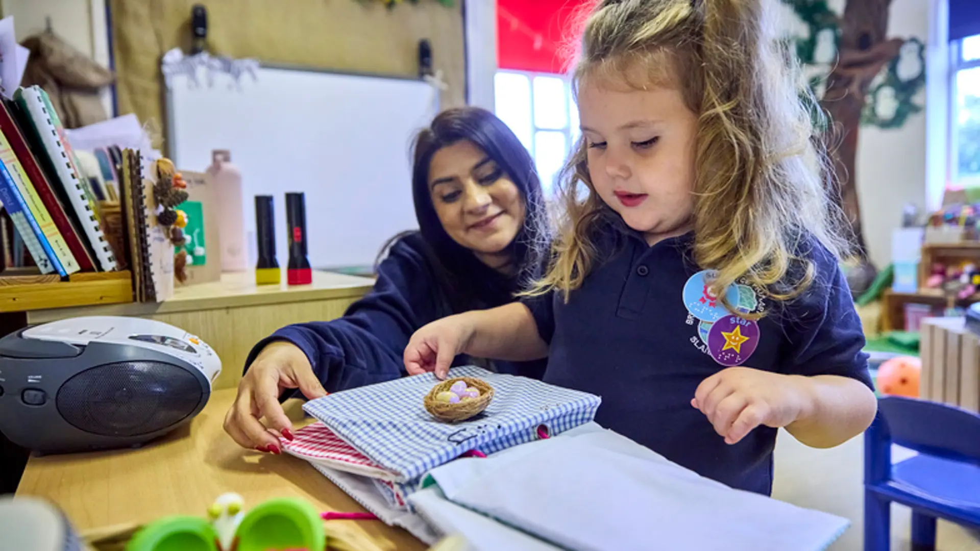 A young girl being supported by her Habilitation Specialist at nursery.