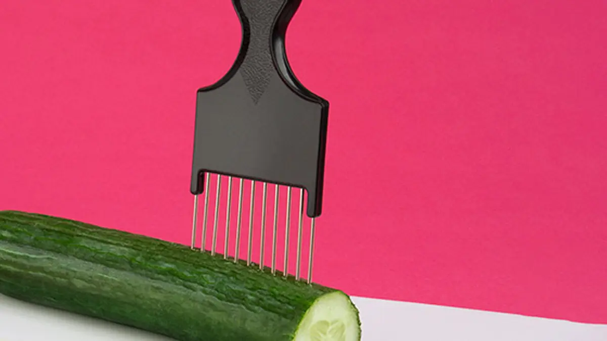 A comb in a cucumber to be used as a guide to help chop evenly.