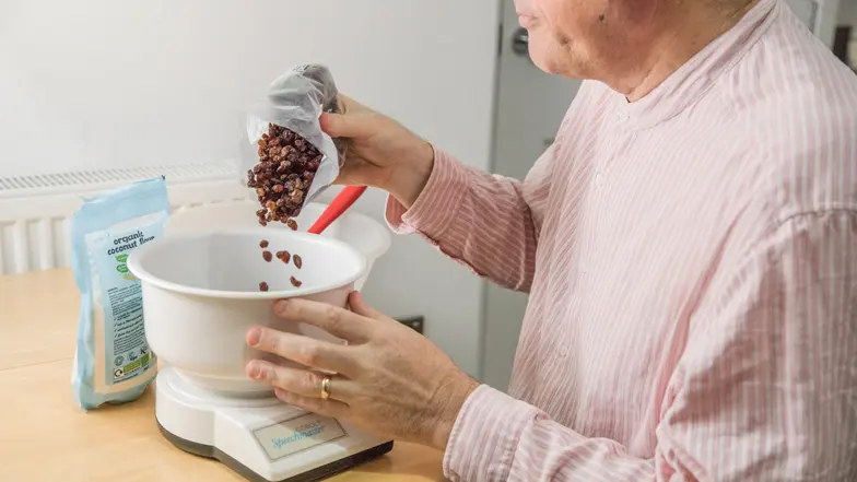 A man pouring some raisins into a set of talking kitchen scales