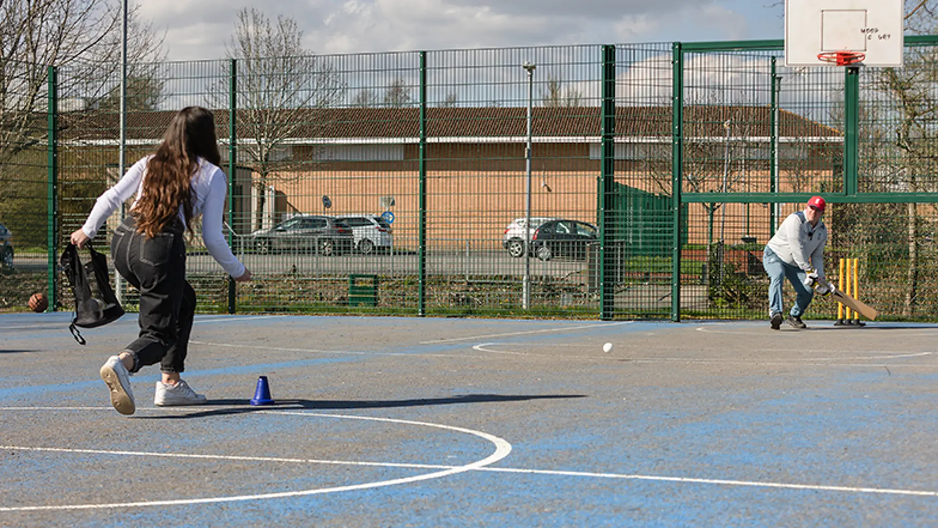 Two people playing cricket on an astroturf court.