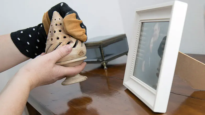 Person is dusting ornaments using a sock on their hand. 