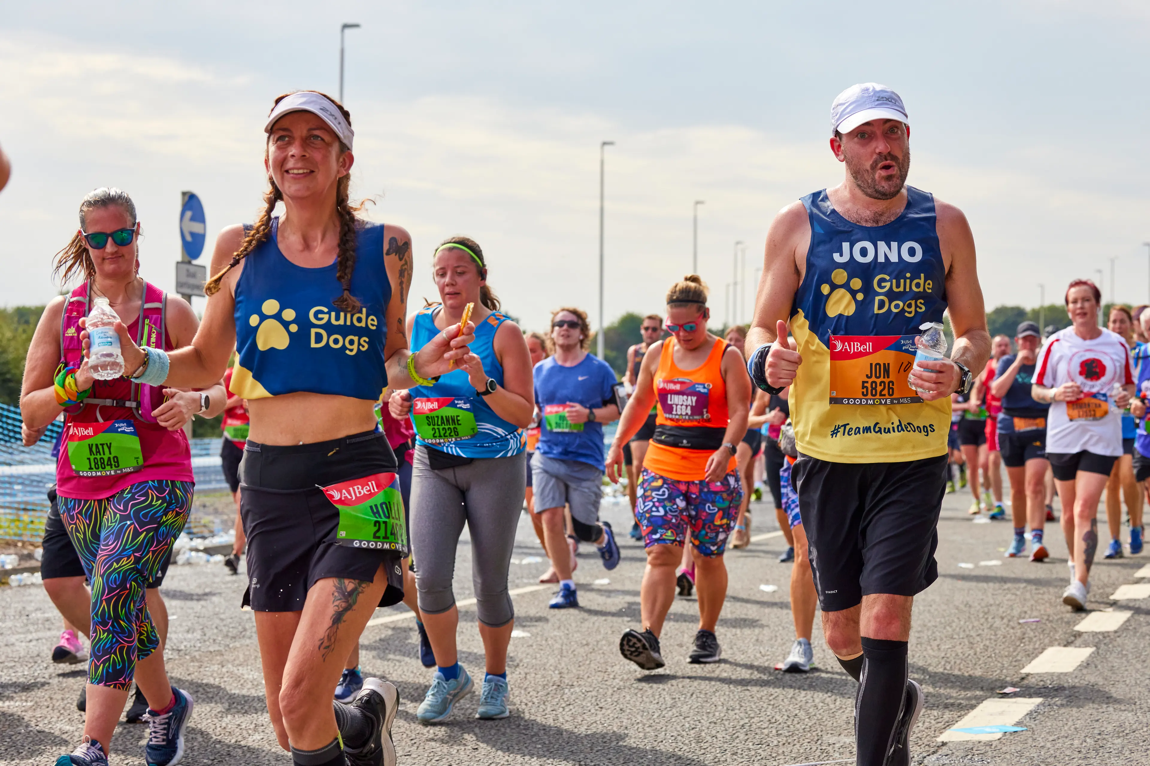 Two runners for Guide Dogs run amongst other race entrants.