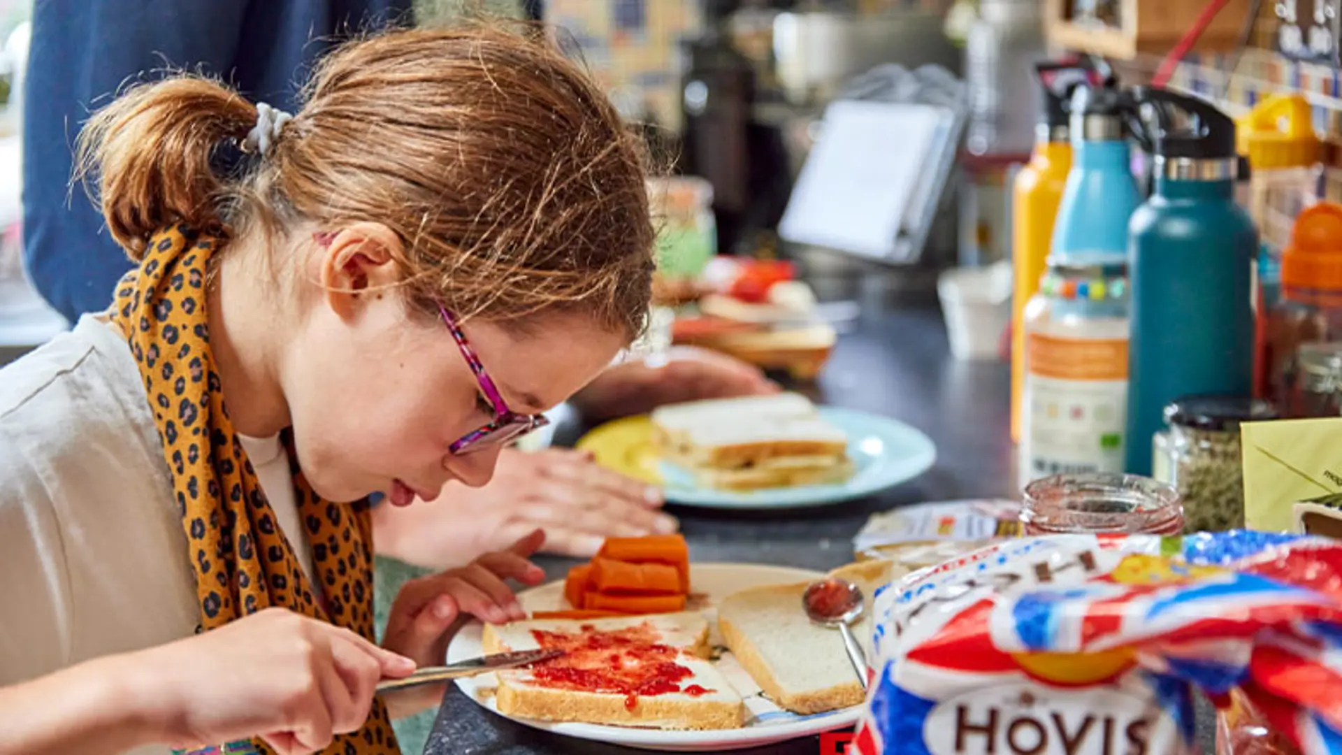 A child with vision impairment making a sandwich in her kitchen. 