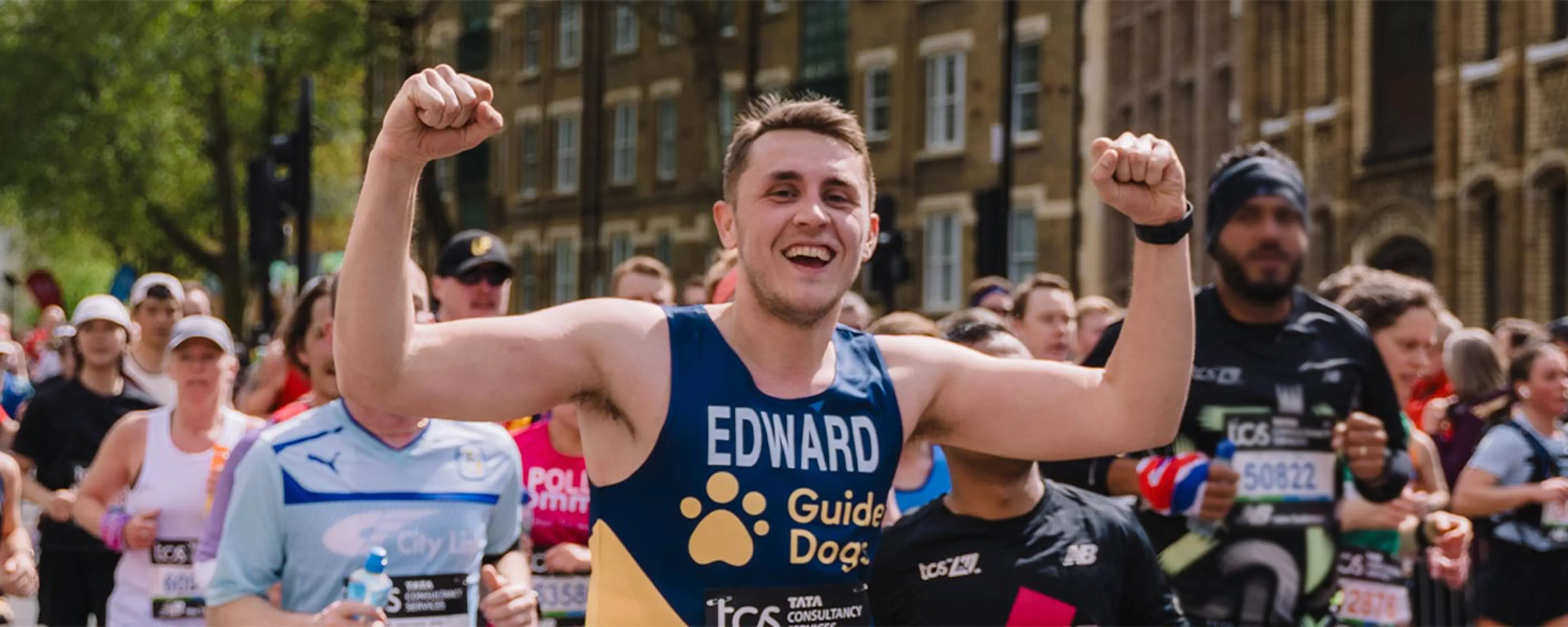 London Marathon runner Edward running and smiling to the camera at London Marathon.