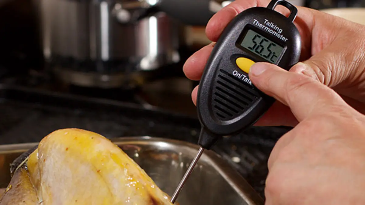 Using a talking thermometer to read the temperature of a roast chicken. 
