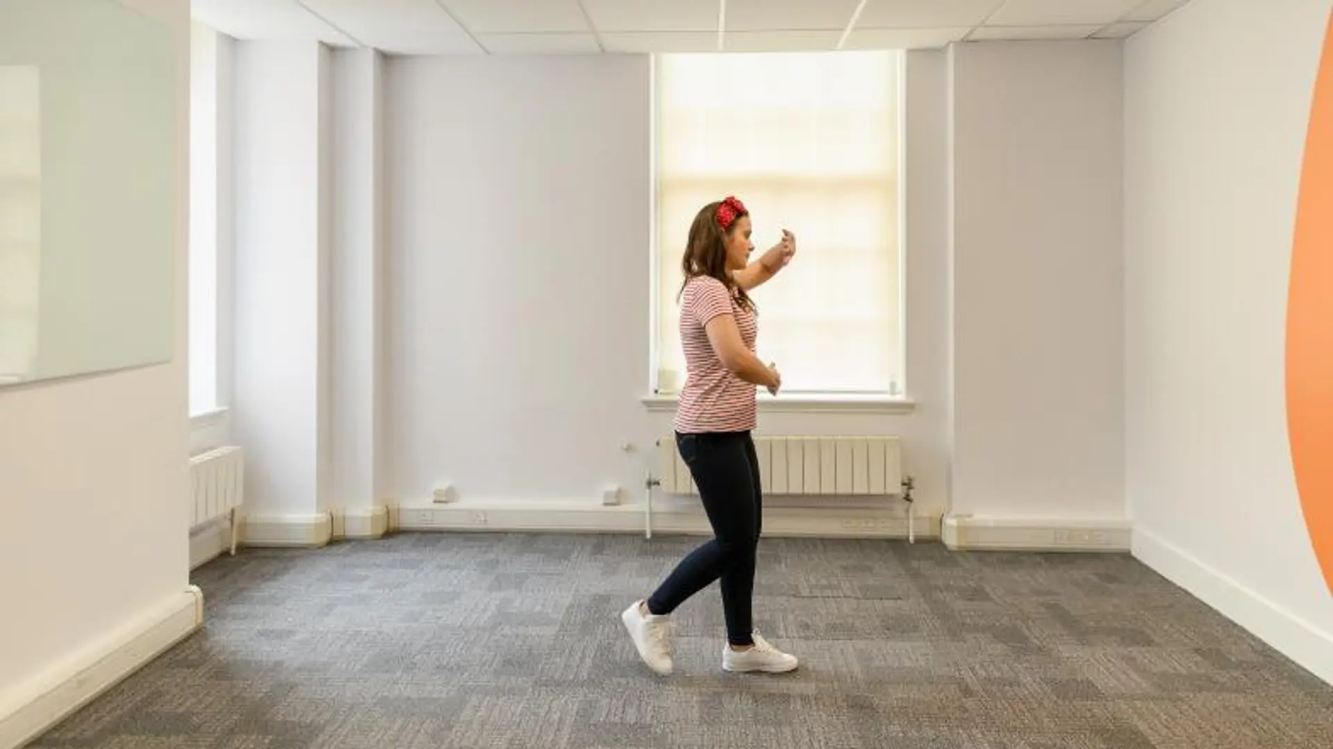 A woman walking from one wall to the other in a meeting room, demonstrating the squaring off technique.
