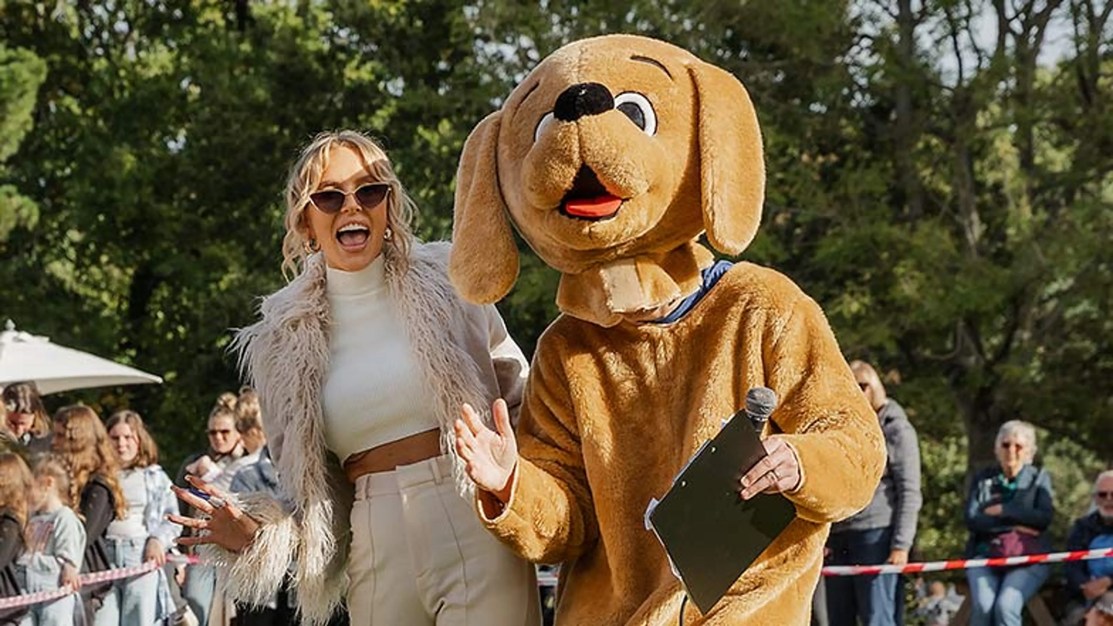Faye Winter standing next to a person in a guide dogs outfit  looking at camera laughing