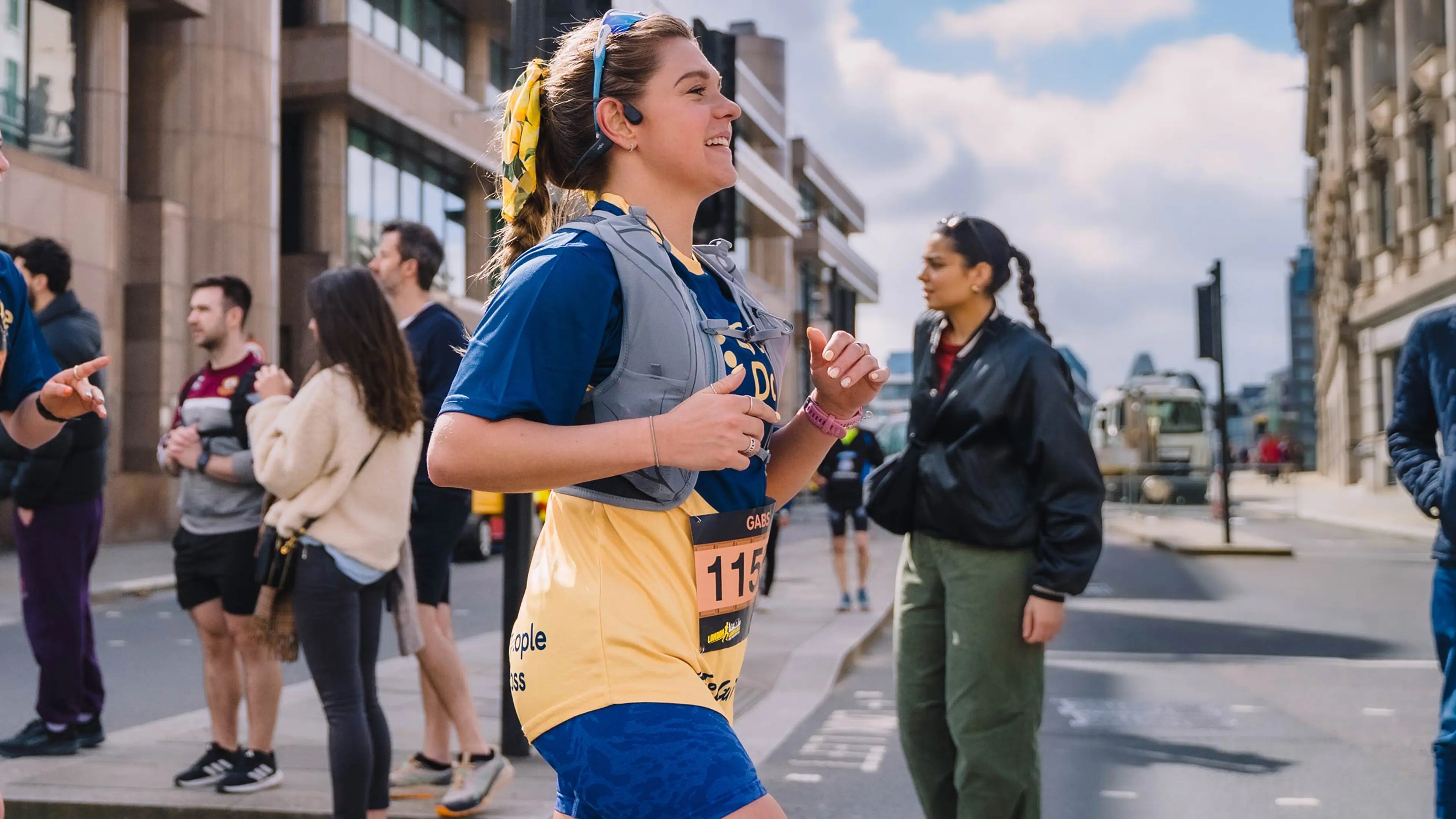 A runner in a Guide Dogs T-shirt smiling as she runs in the London Landmarks Half Marathon