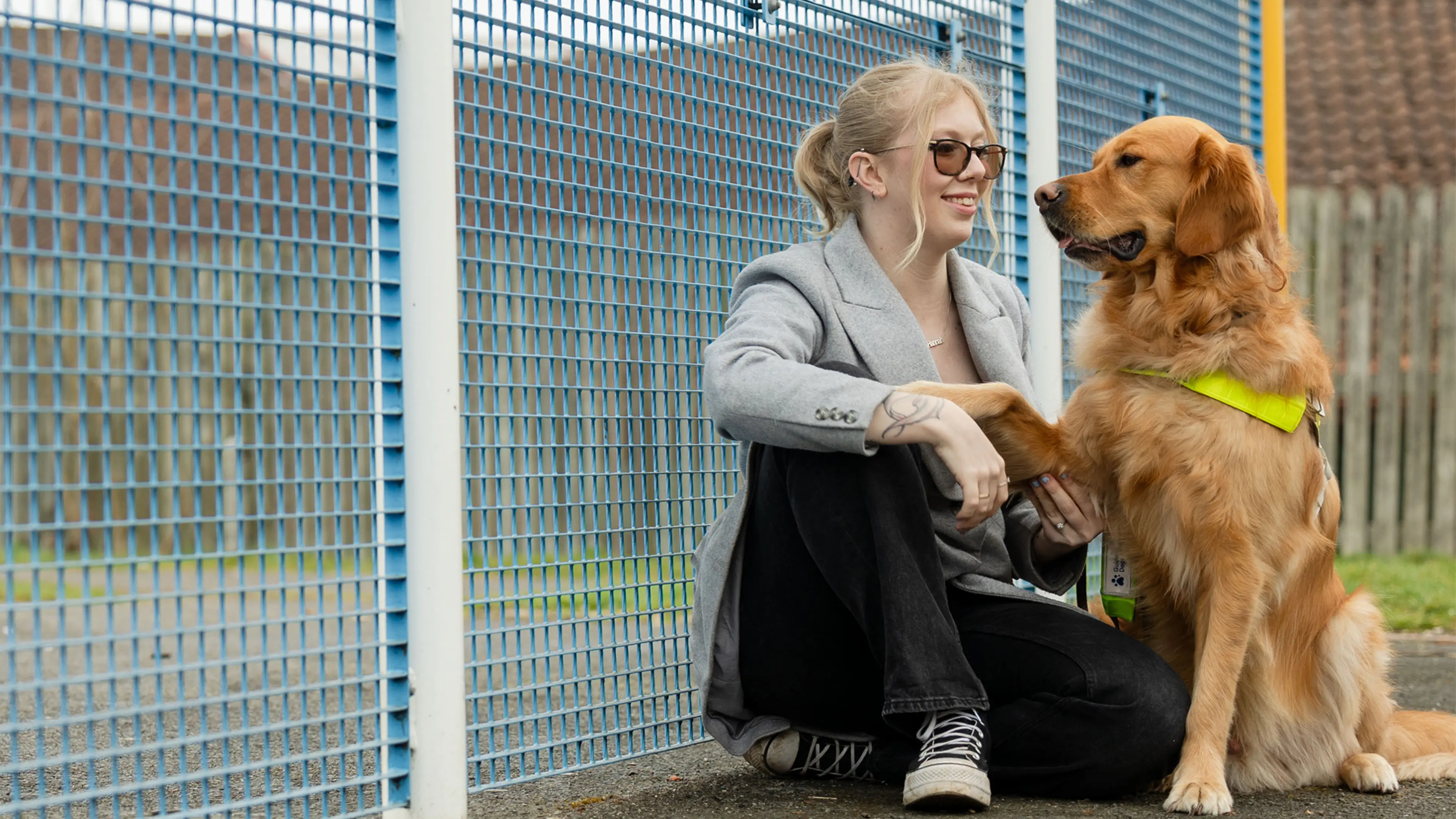 Guide dog owner Hannah sits with her guide dog Morris, he rests his paw on her knee as she smiles at him.