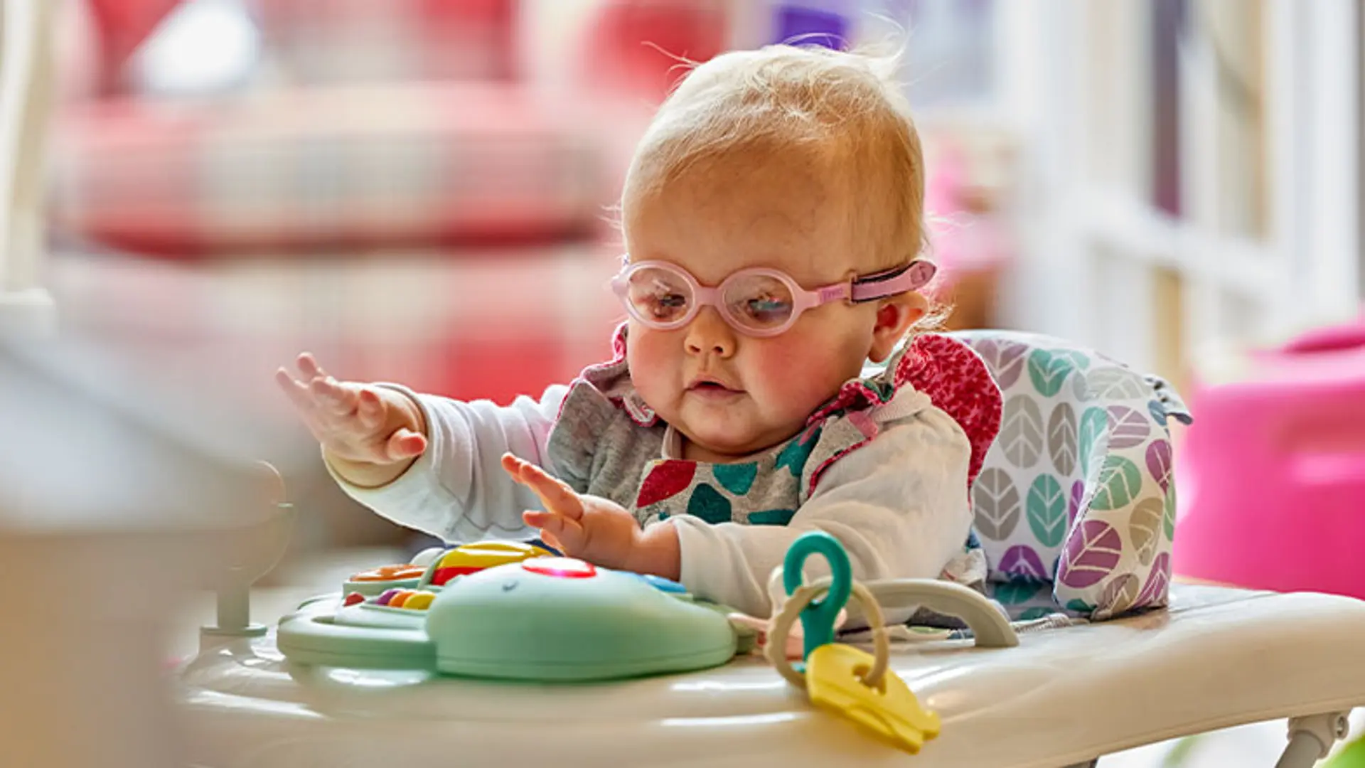 Margot sits in her highchair, playing with some toys.