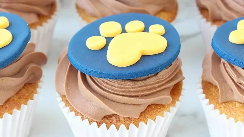 A cupcake with a Guide Dogs people-paw logo on the top