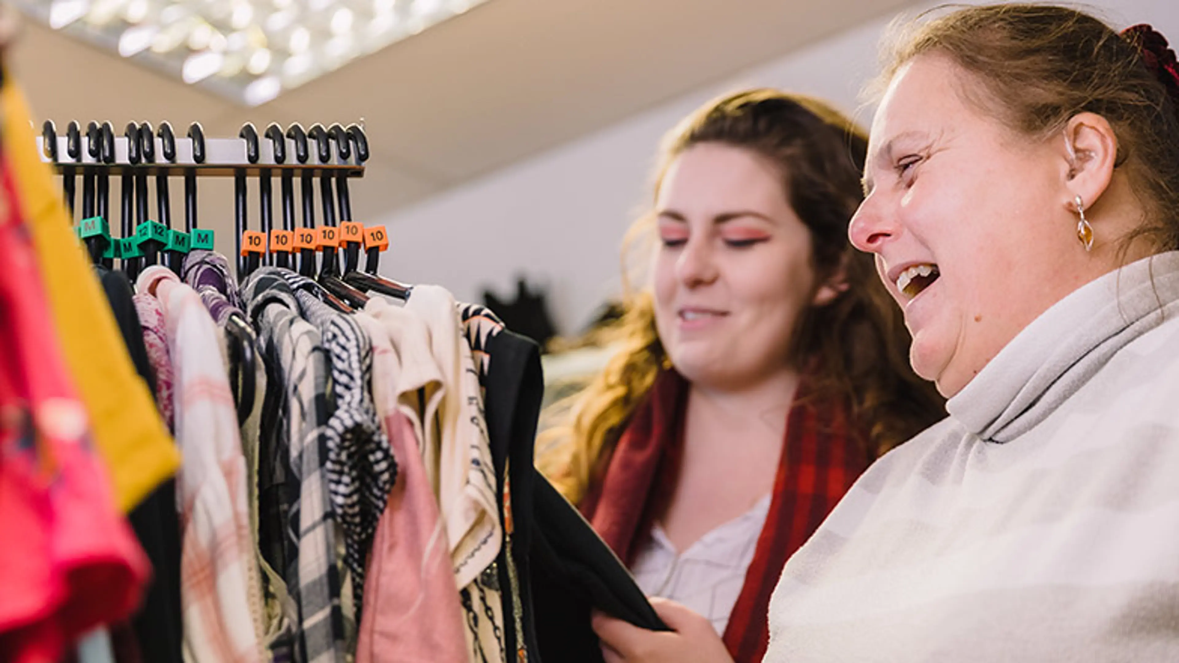 A person with sight loss clothes shopping with her sighted guide