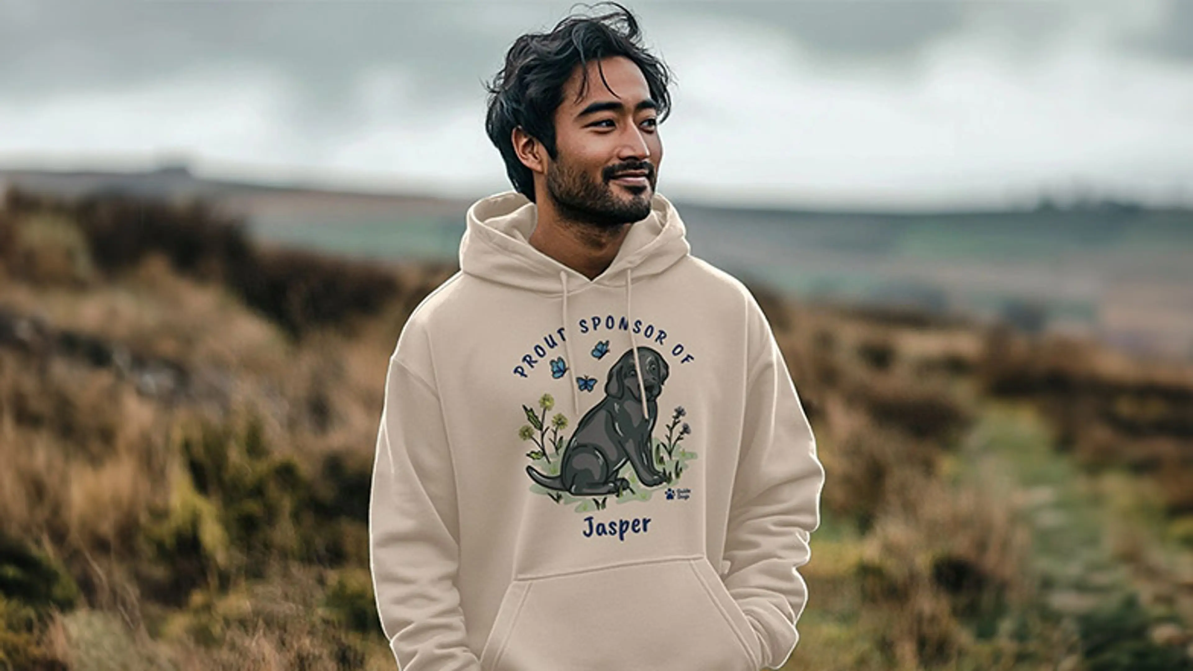 A man in the countryside wearing a sweatshirt with sponsored pup Jasper design.