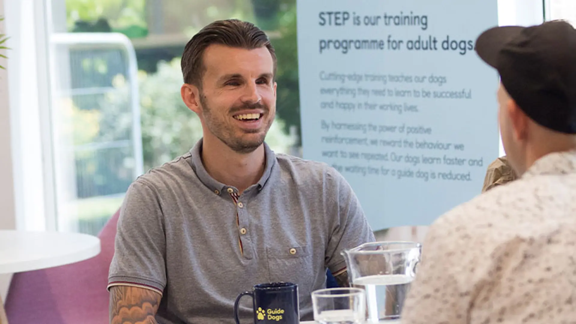 A man with sight loss chats with a Guide Dog employee