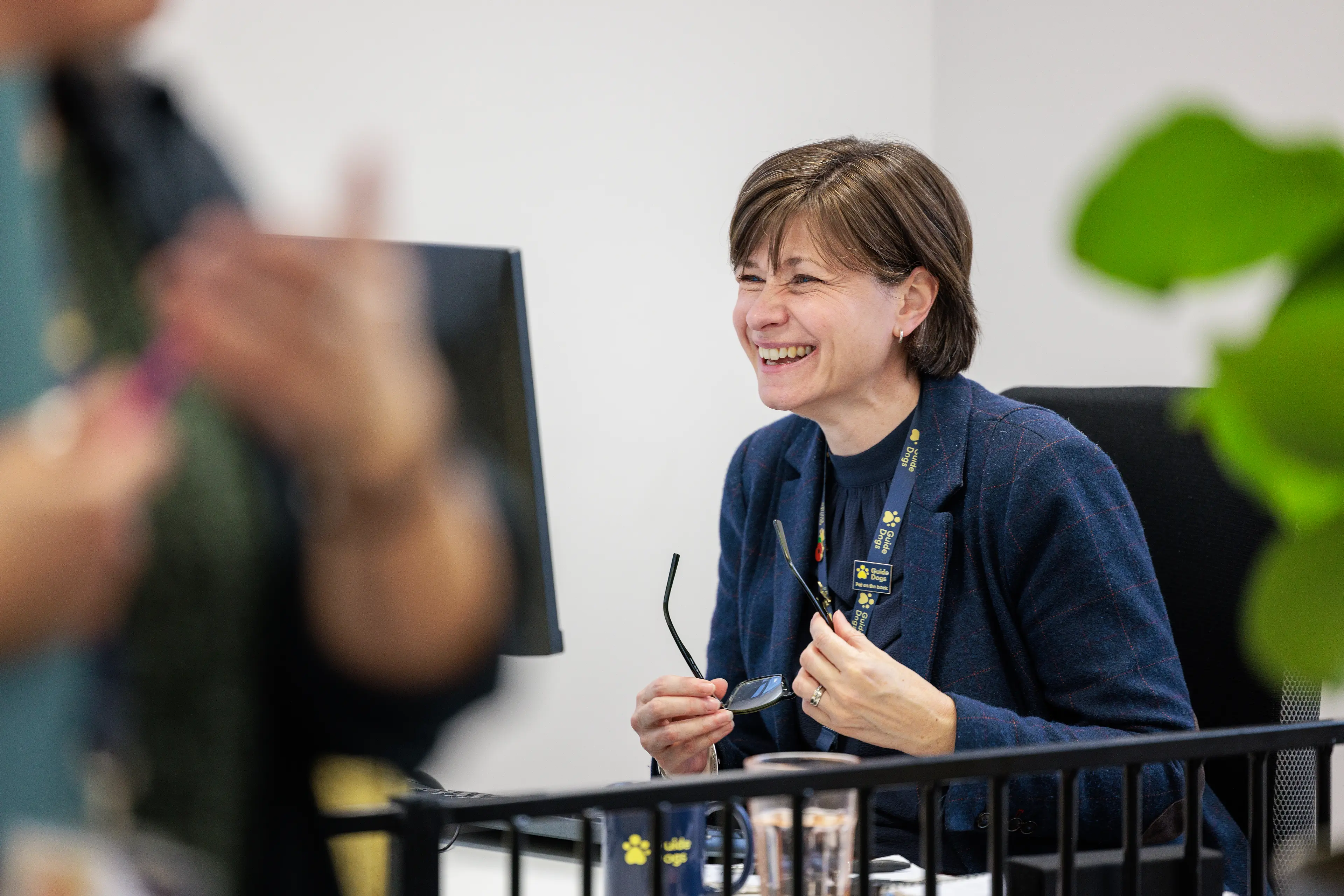 A lady is laughing in an office.