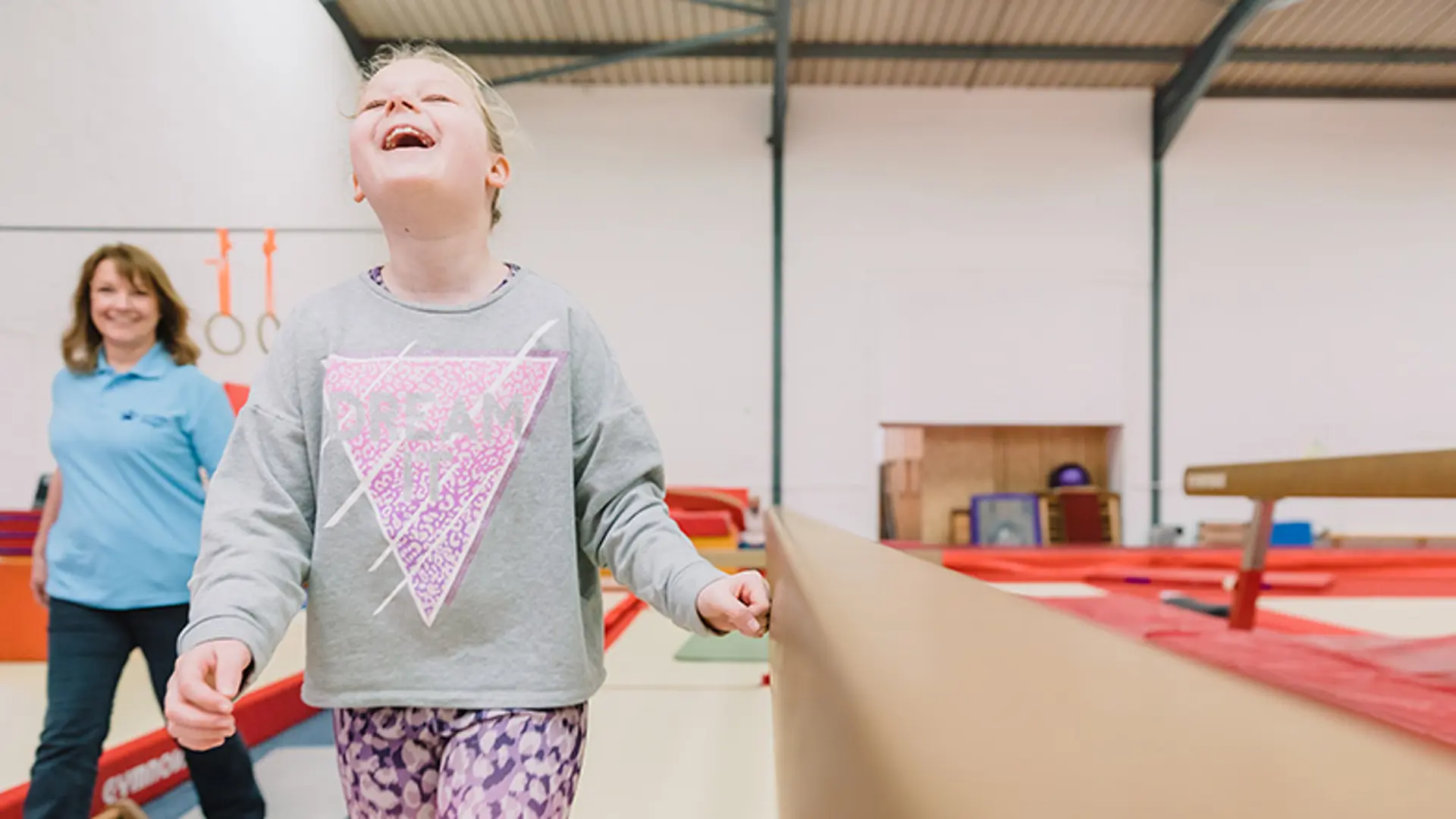 Oashia smiling in gymnastics with Guide Dogs habilitation specialist