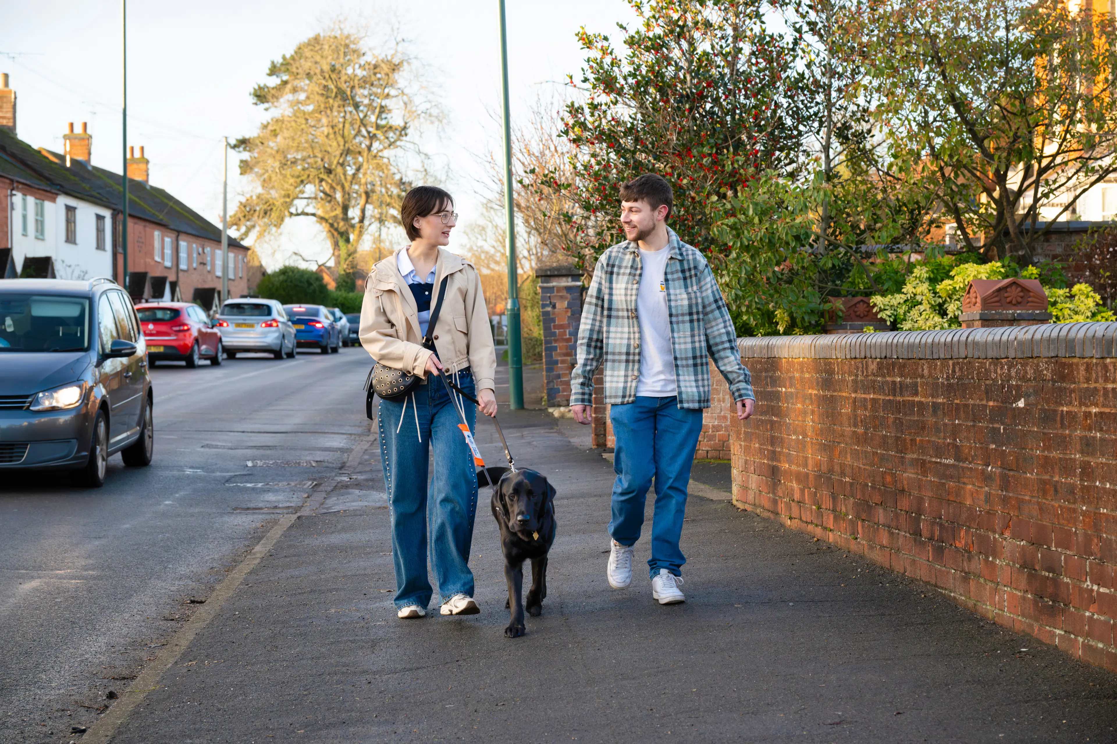 Volunteers walk a guide dog along a pavement