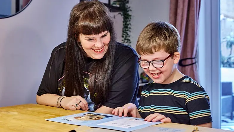 Rex, and his mum, Lorna, read a book together with enlarged font.