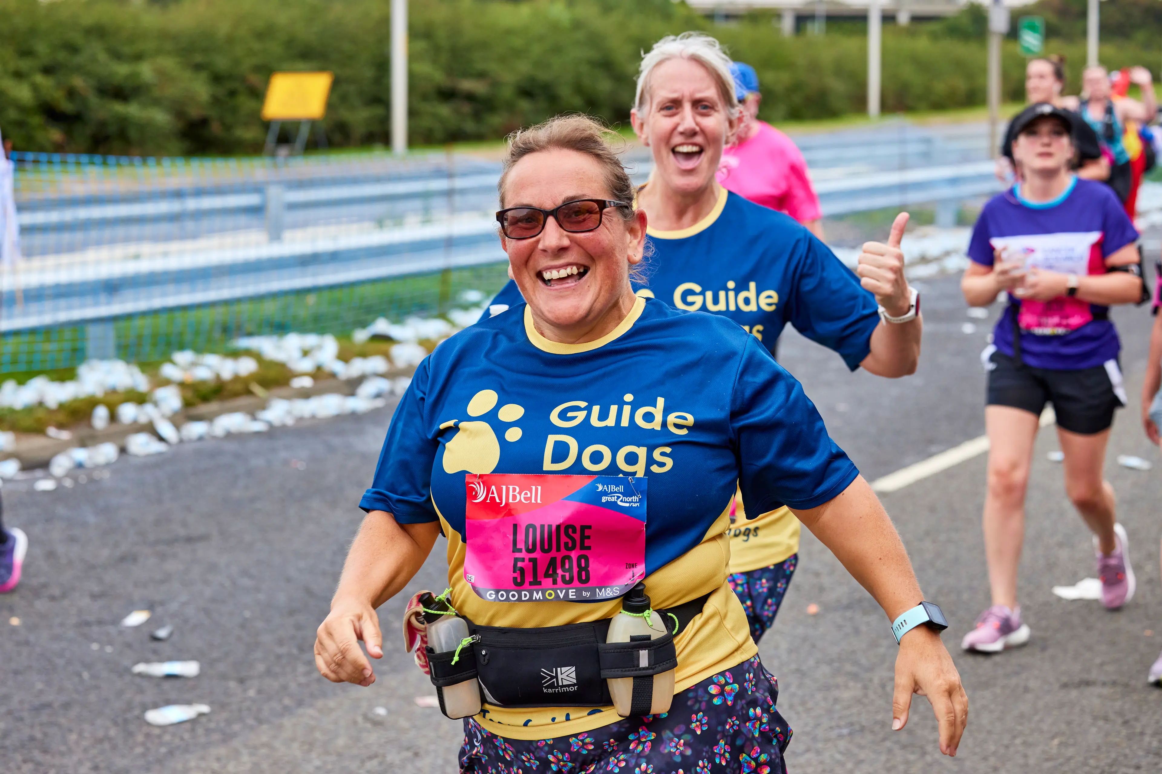 Runners in a race wearing Guide Dogs t-shirts smile at the camera.