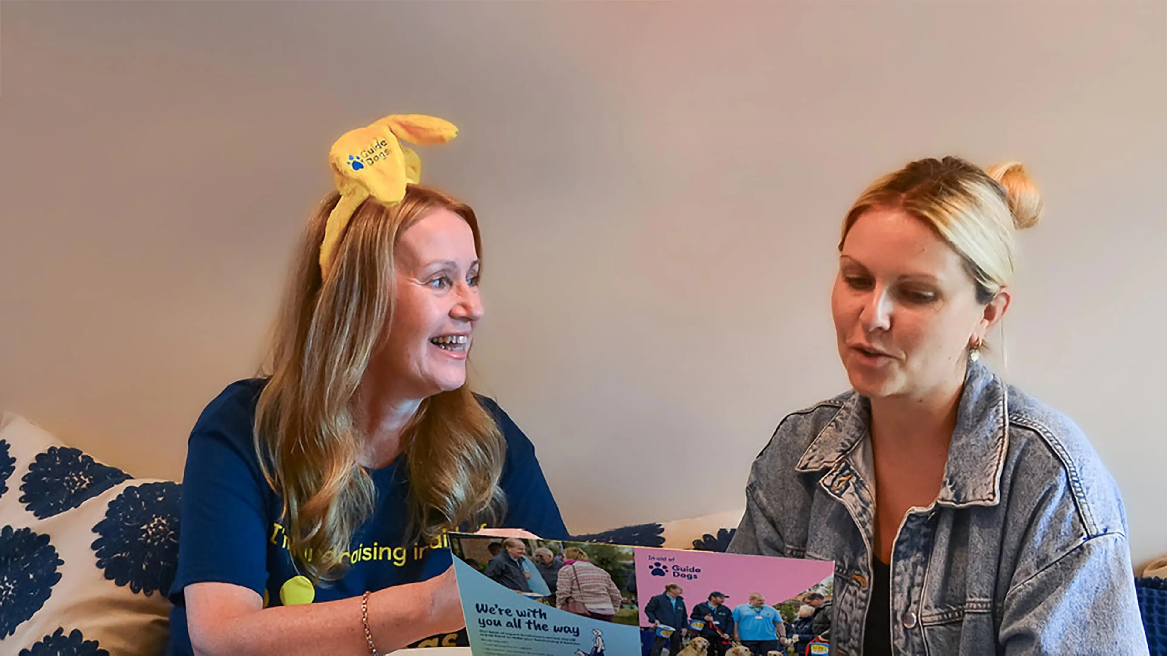 A Guide Dogs Puppy Appeal fundraiser wearing dog ears talks to a business owner