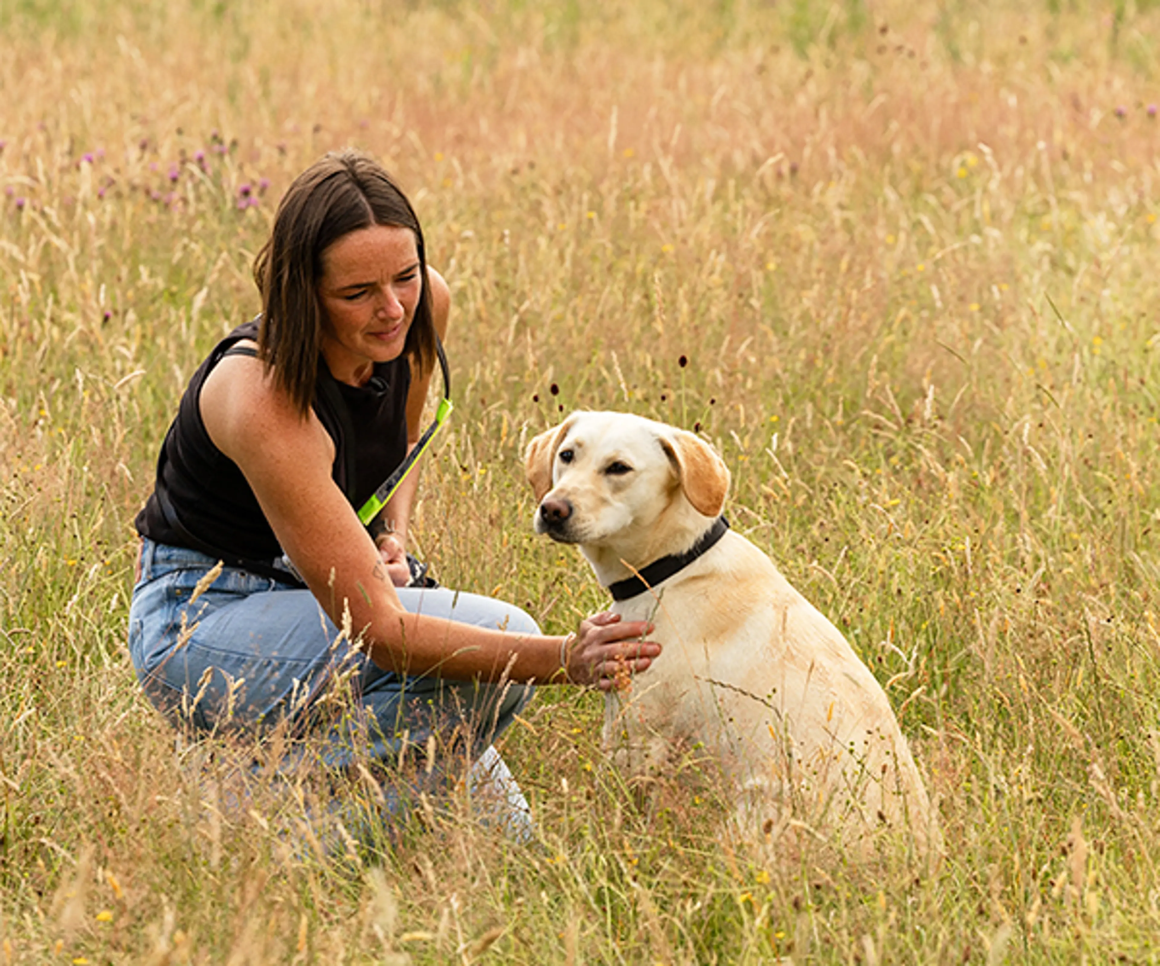 Volunteer puppy raiser Philippa with a guide dog puppy in a sunny field