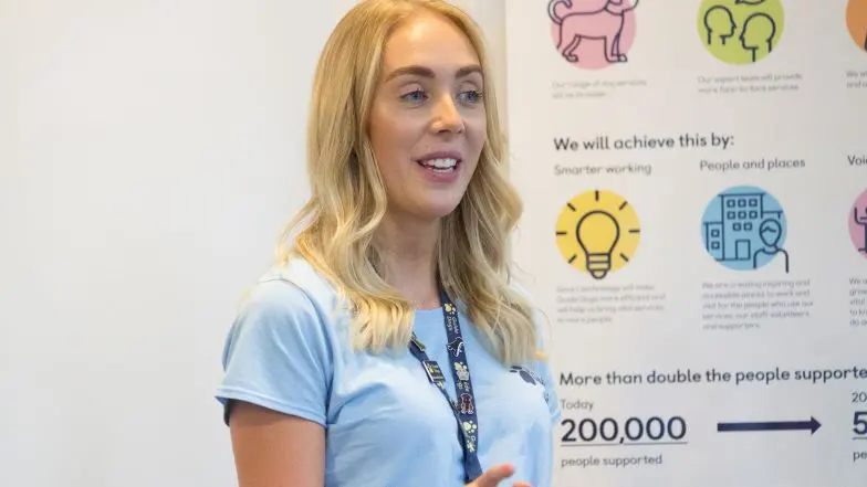 A Guide Dogs staff member wearing a Guide Dogs t-shirt and giving a talk