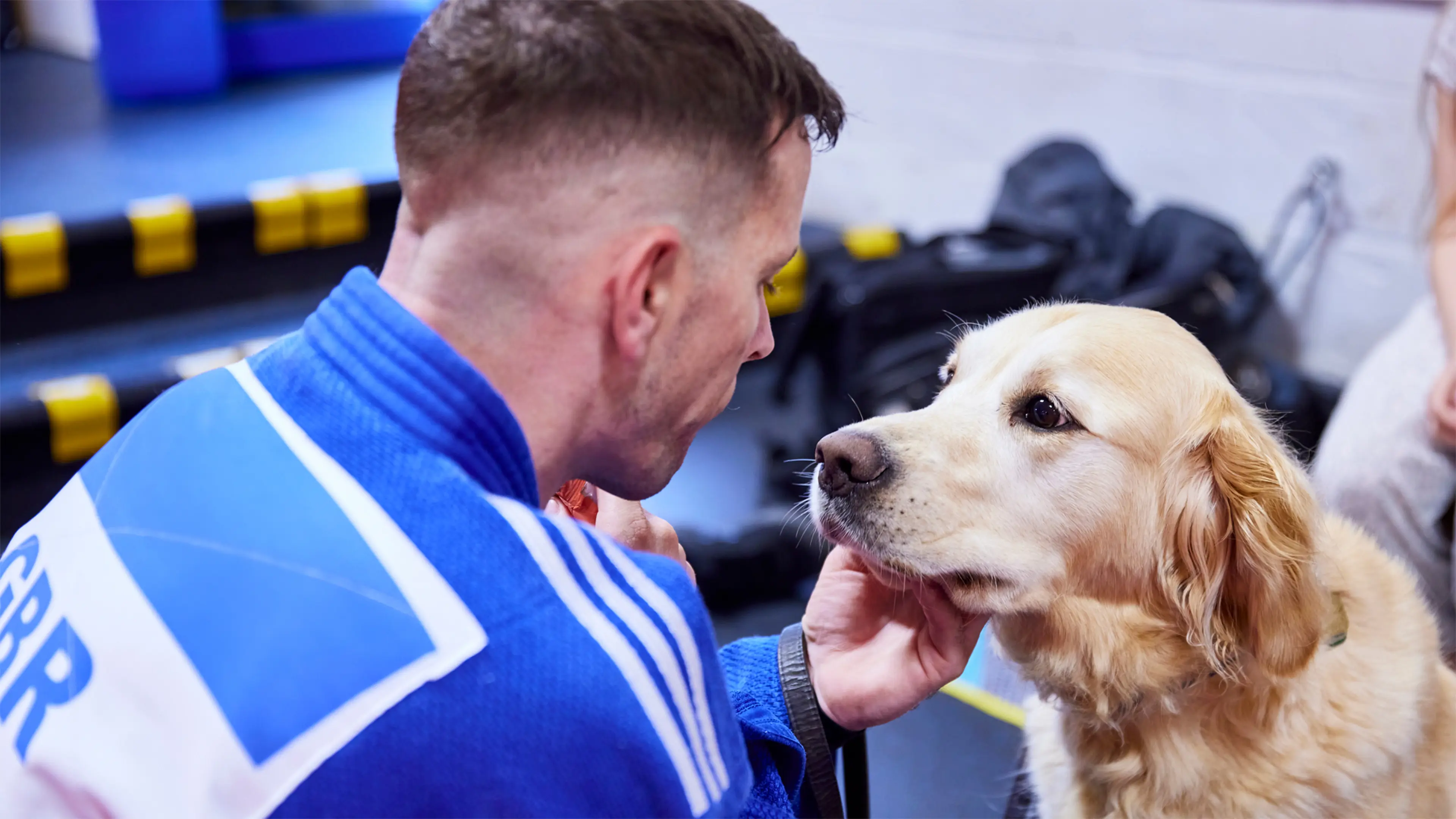 Guide dog owner Scott wears his Judo kit at practice, as he gives his guide dog Milo a scratch under the chin.