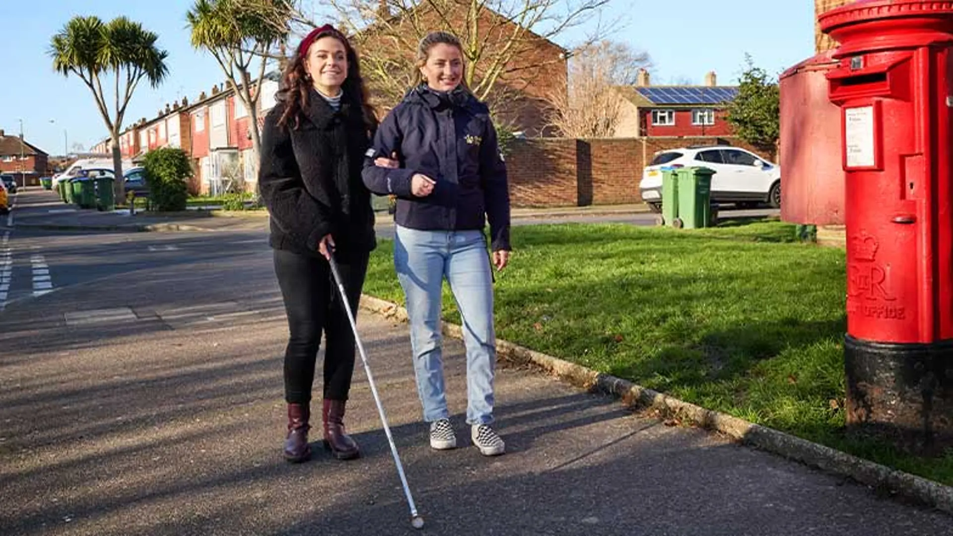 Taylor and a Visual Rehabilitation Specialist walk alongside each other. Taylor uses a long cane.