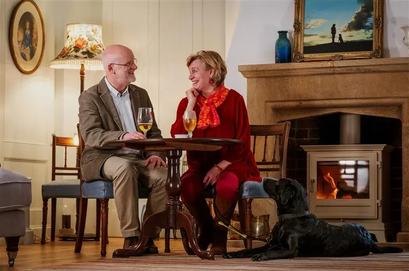 Volunteers sit at a table in a pub with a guide dog puppy lying beside them
