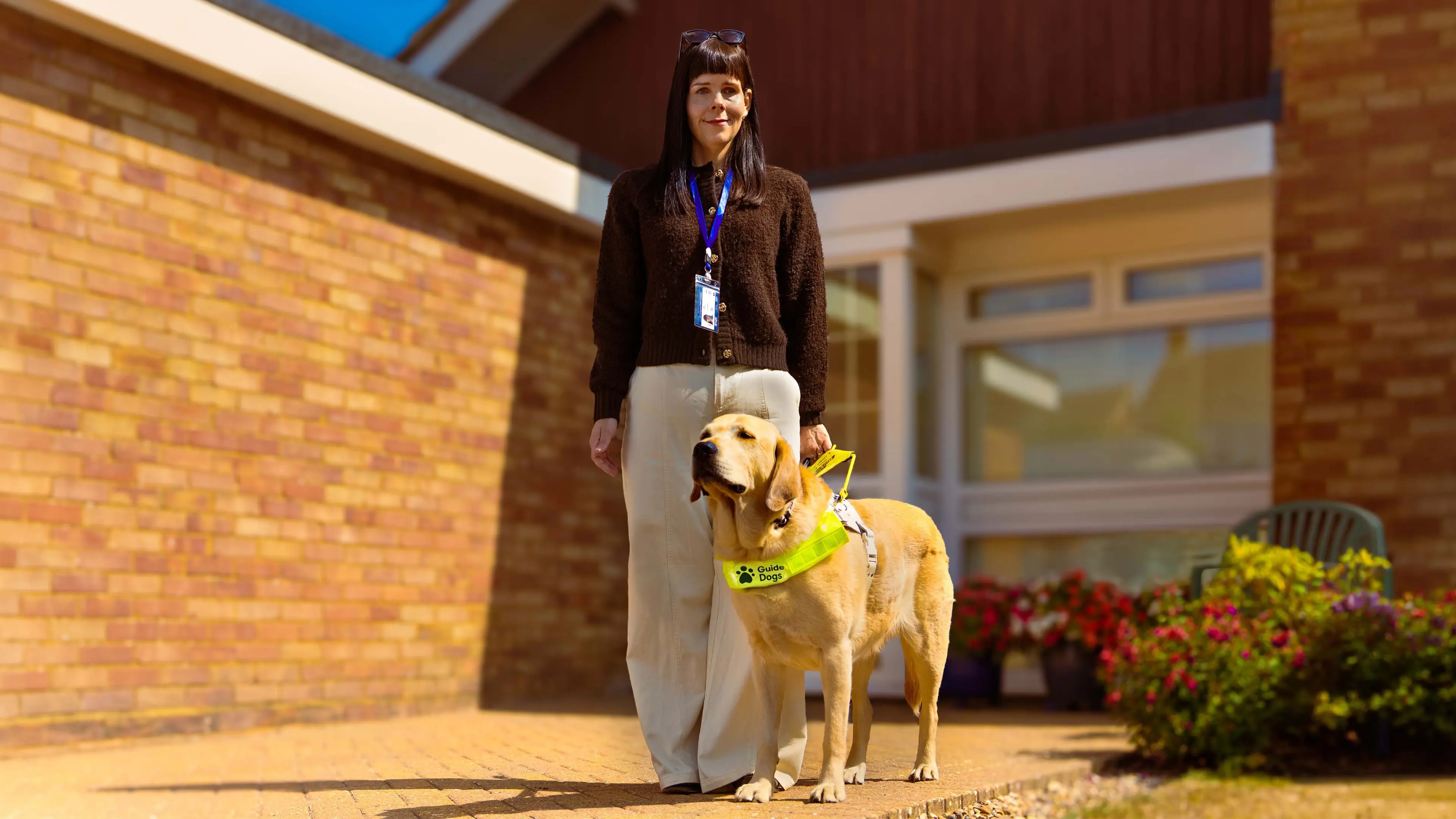 Lorna stands outside her home with her guide dog by her side.