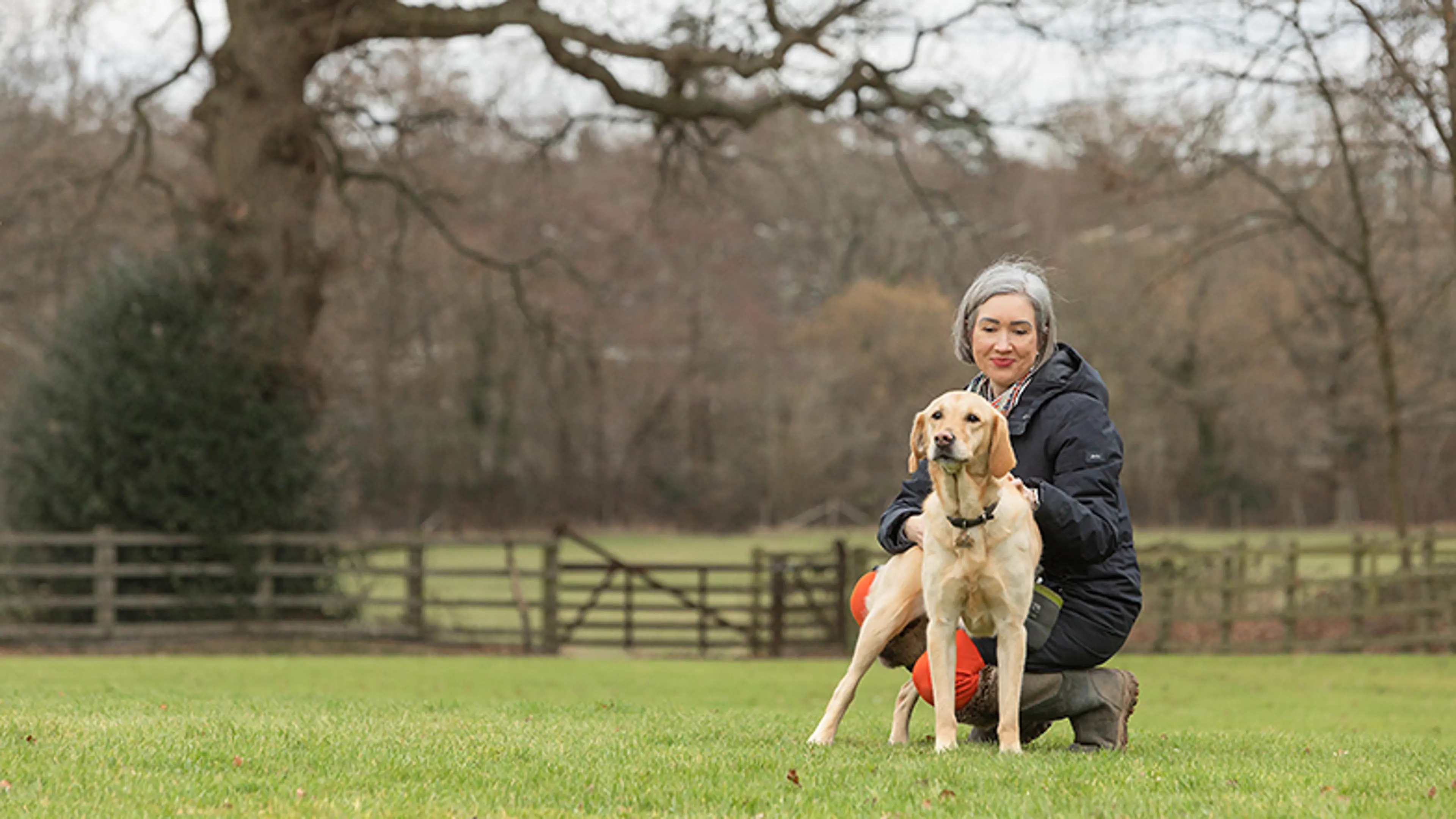 Labrador Maggie and owner Melanie standing in a field together.