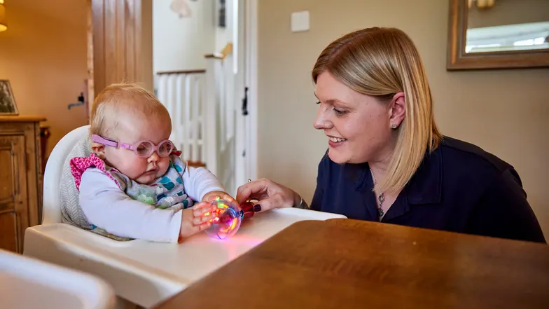 A habilitation specialist smiles as she plays with toys with a young service user.
