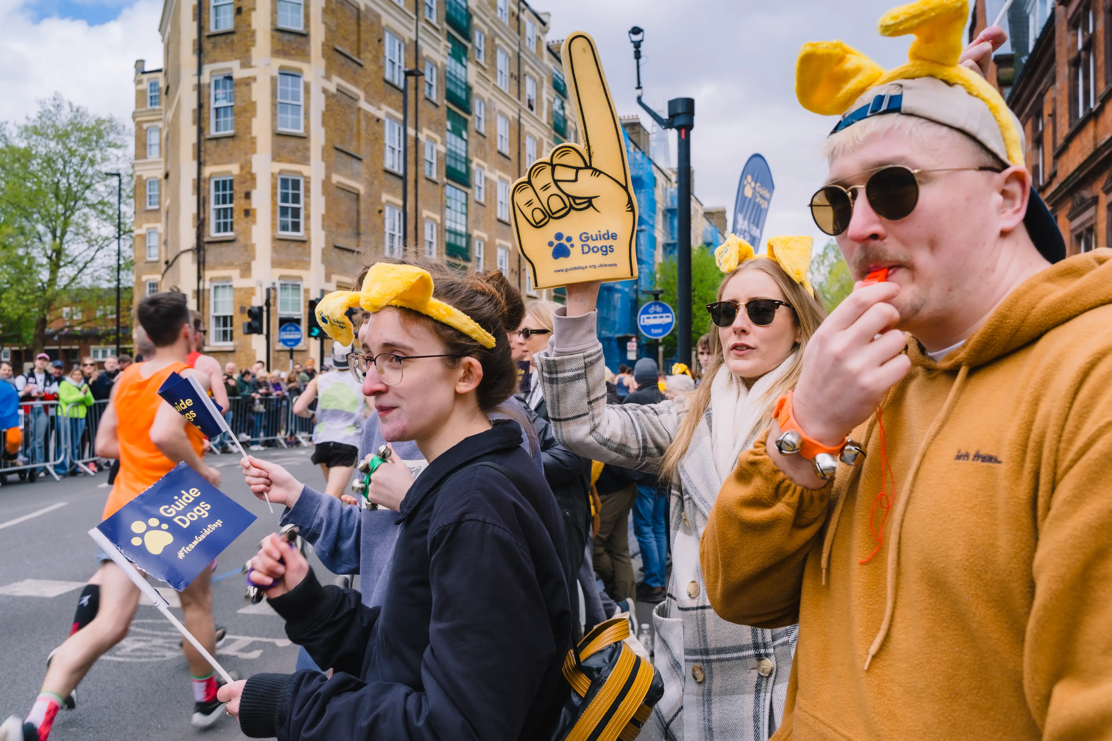 Photos of cheerpoint volunteers from the London Marathon 2024, wearing dog ears and a foam finger.