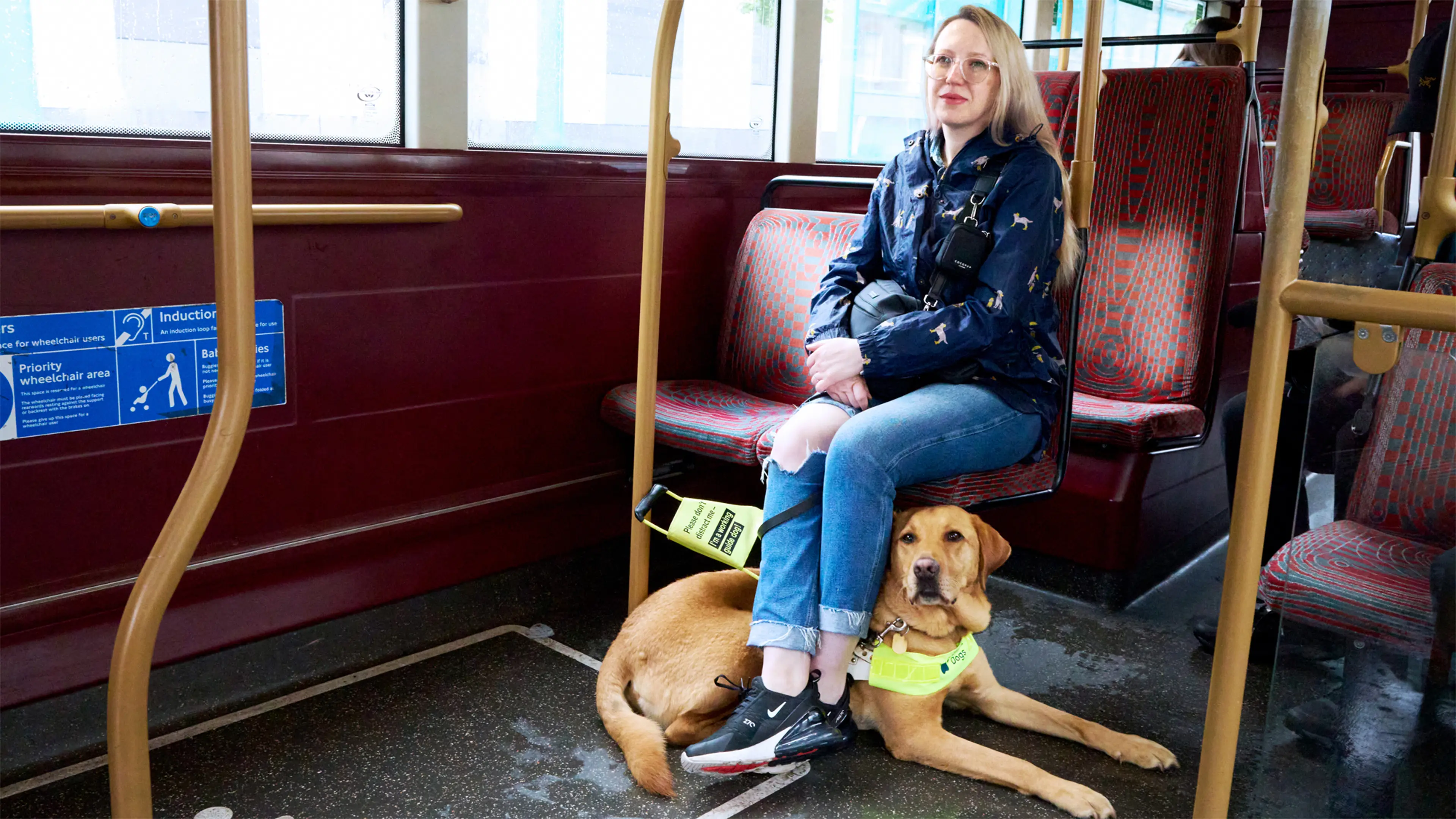 Guide dog owner Emma sits on a London bus, her guide dog Archie lies patiently under her legs.