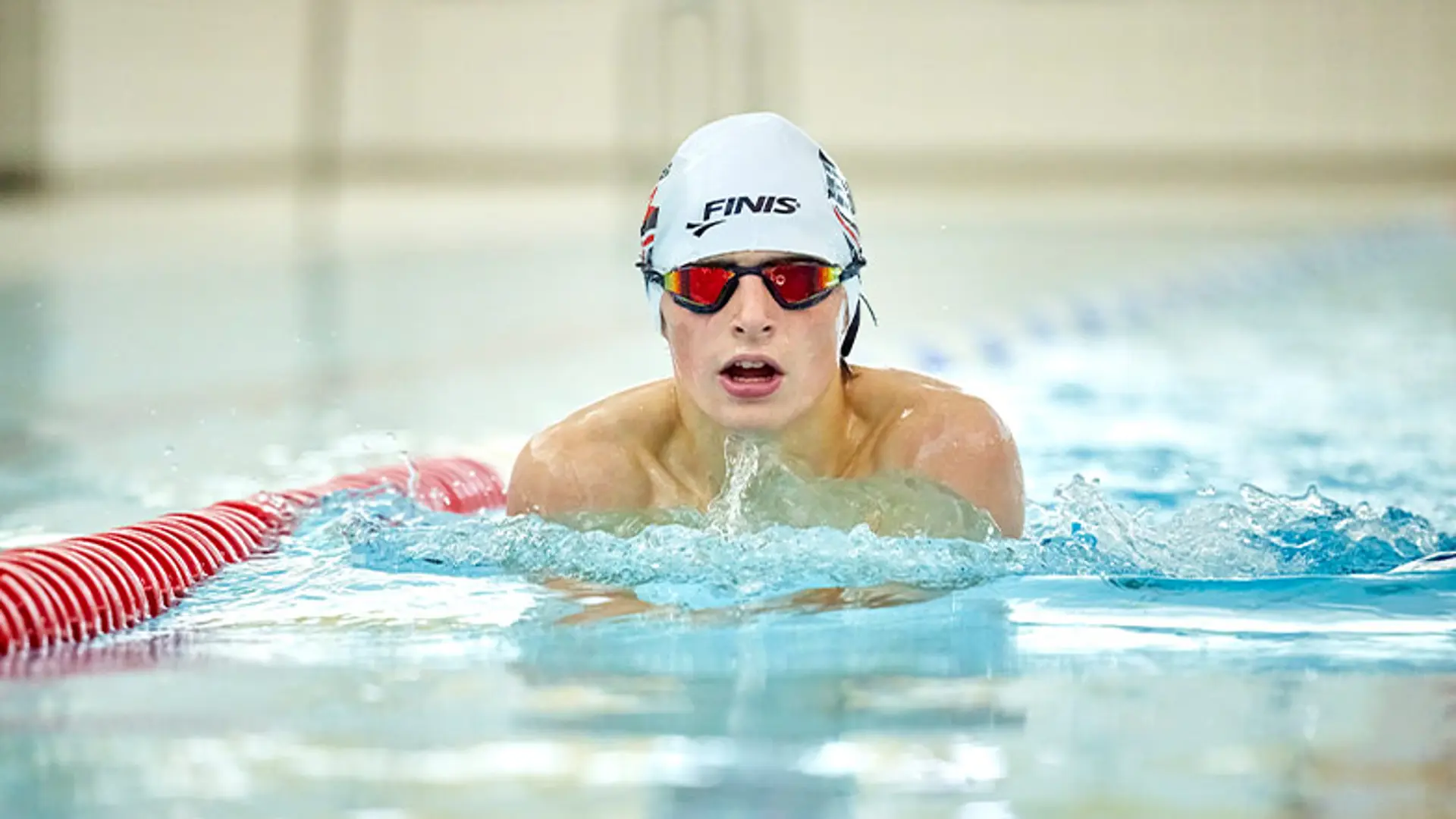 Archie swims toward the camera. He is wearing a swimming cap and goggles.