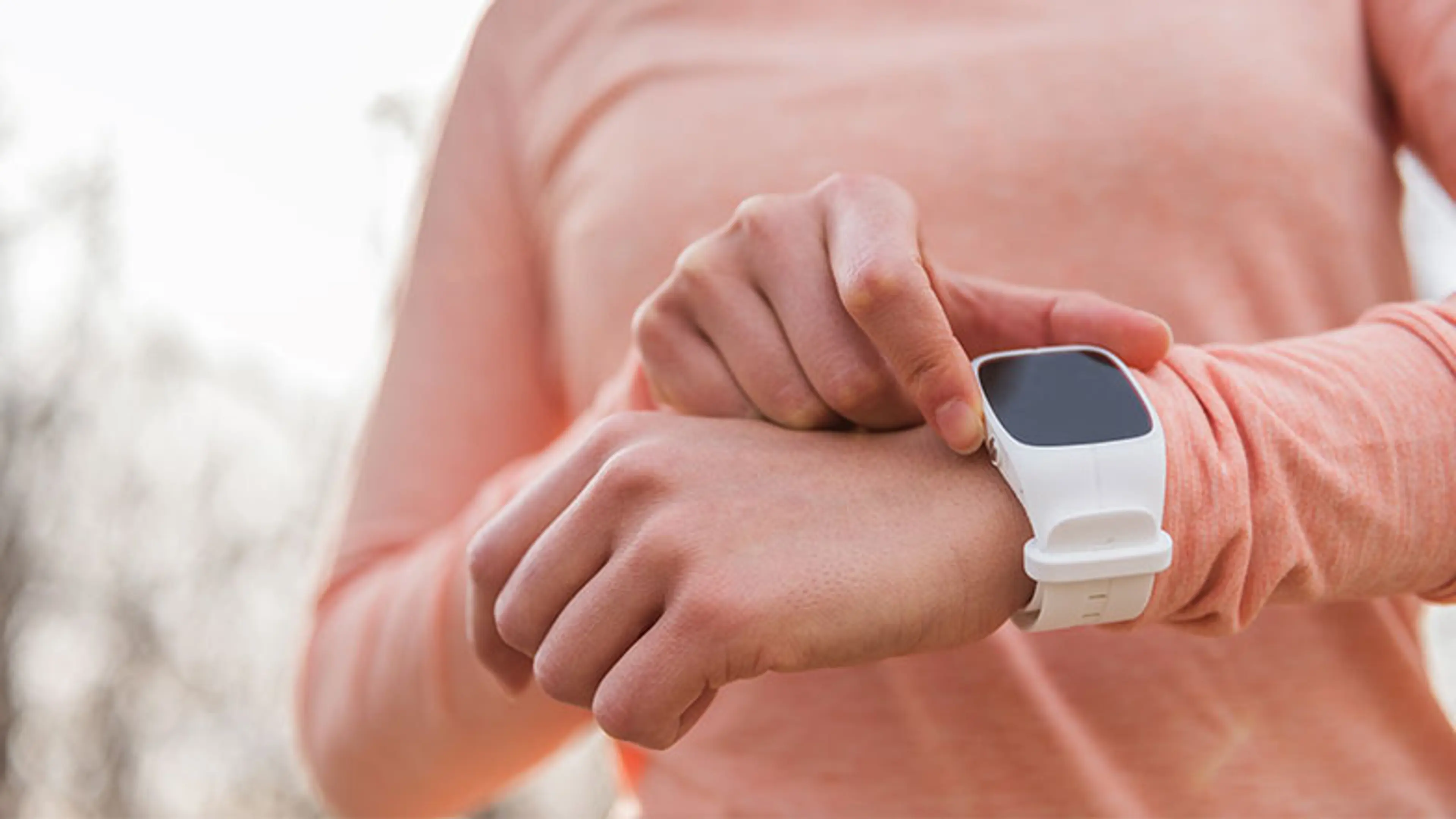 An image of a woman looking at her smart watch whilst on a run
